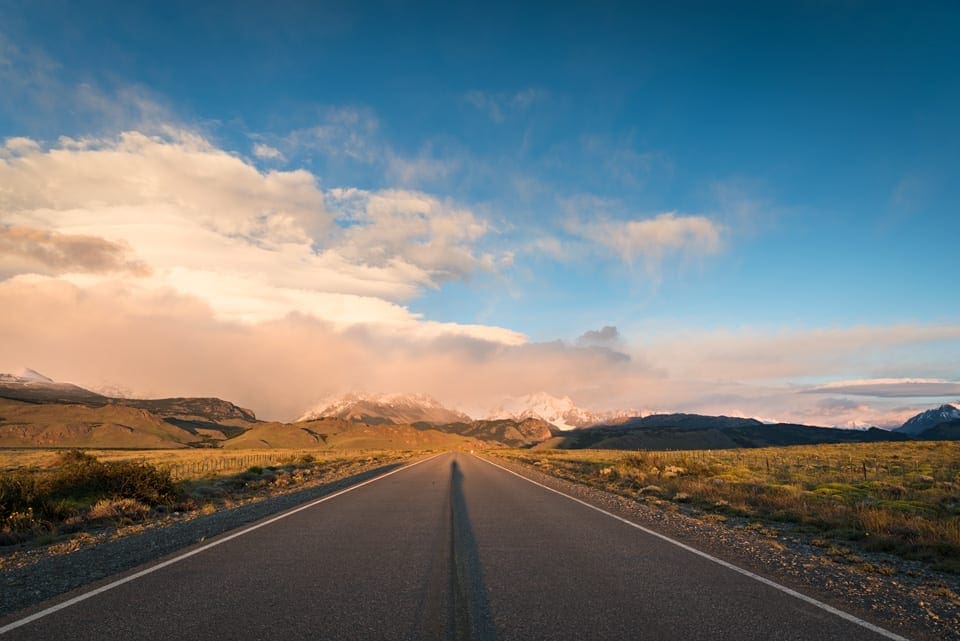 Renting a car and driving in Patagonia: a complete guide el chalten road sunsrise A road near El Chalten in Argentine Patagonia at sunrise with mountains and clouds in the background
